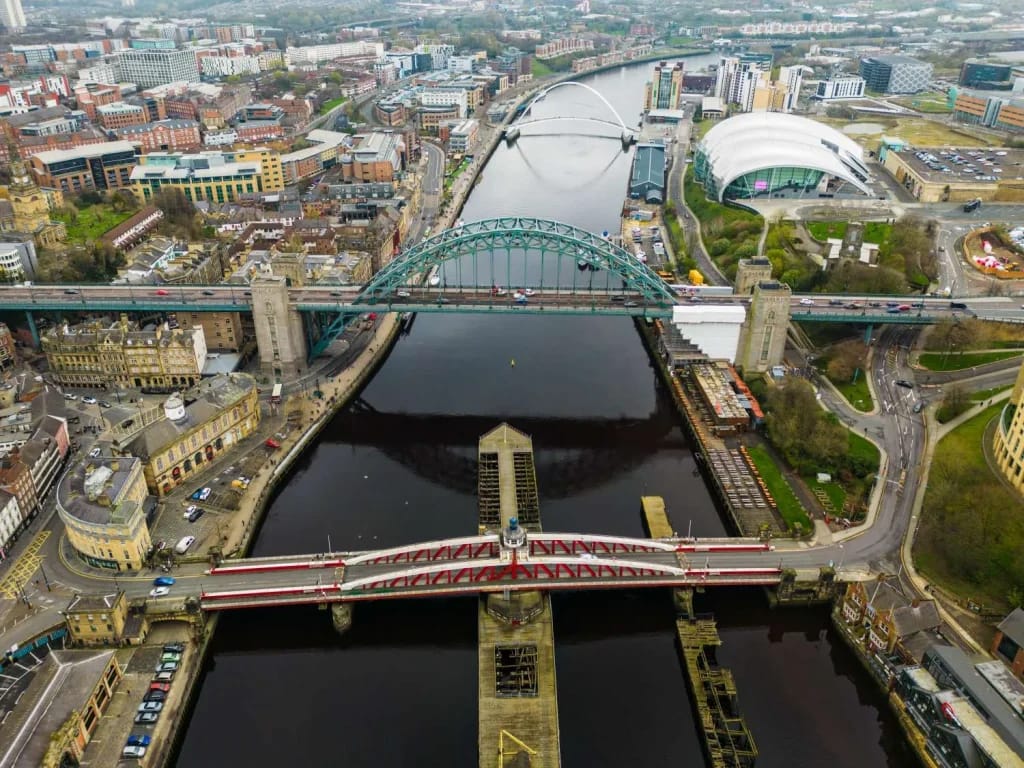 Aerial view of the Tyne Bridge and other bridges spanning the River Tyne in Newcastle upon Tyne, with city buildings on either side.