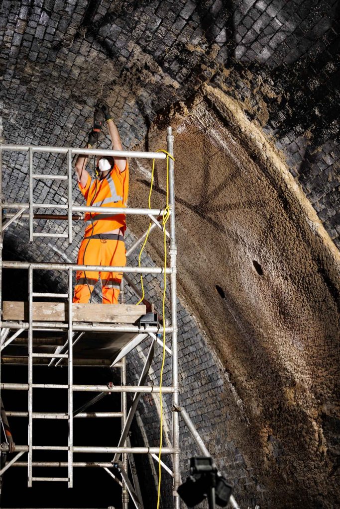 Worker on an access platform inside a large industrial pipe or culvert structure