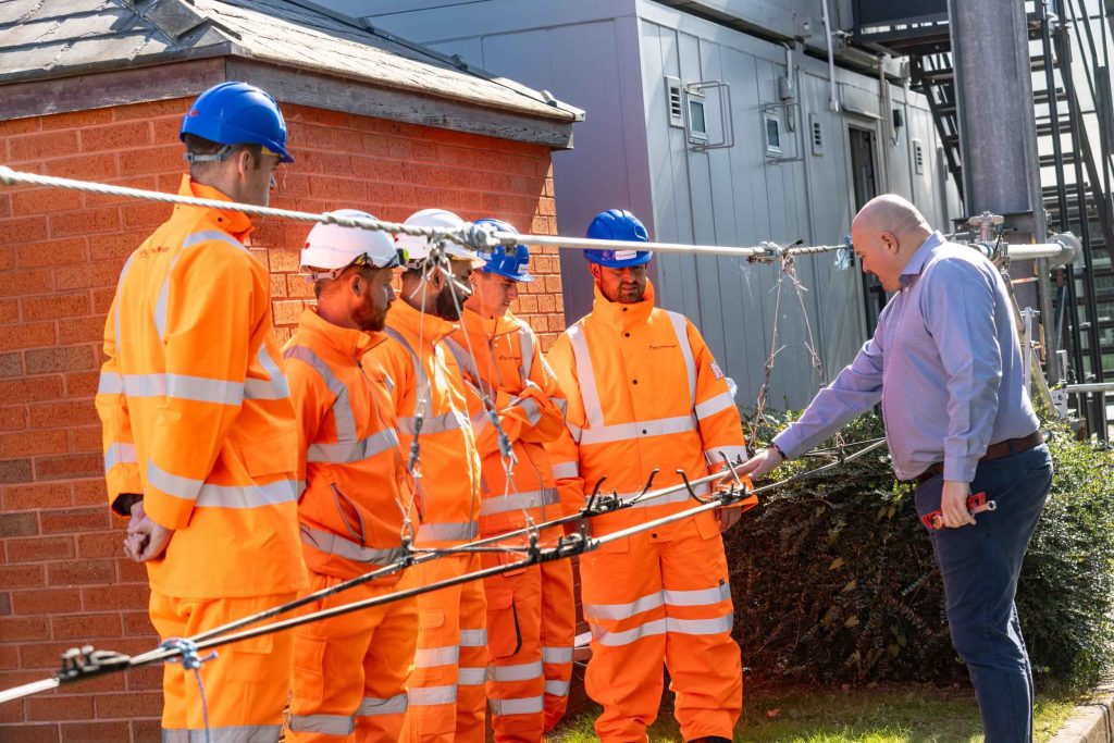 Group of construction workers in hi-vis on site, with a site manager in a shirt and tie shaking hands with the team