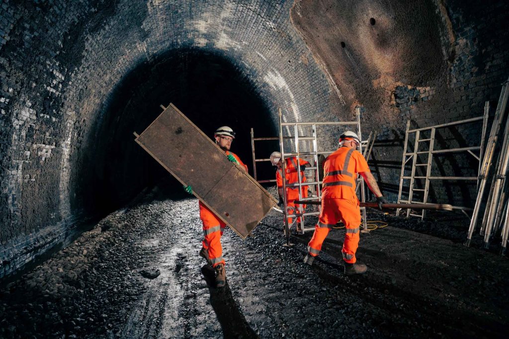 Workers carrying materials inside an underground tunnel construction site