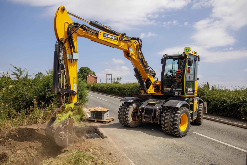 Yellow excavator working at the roadside verge on an infrastructure project