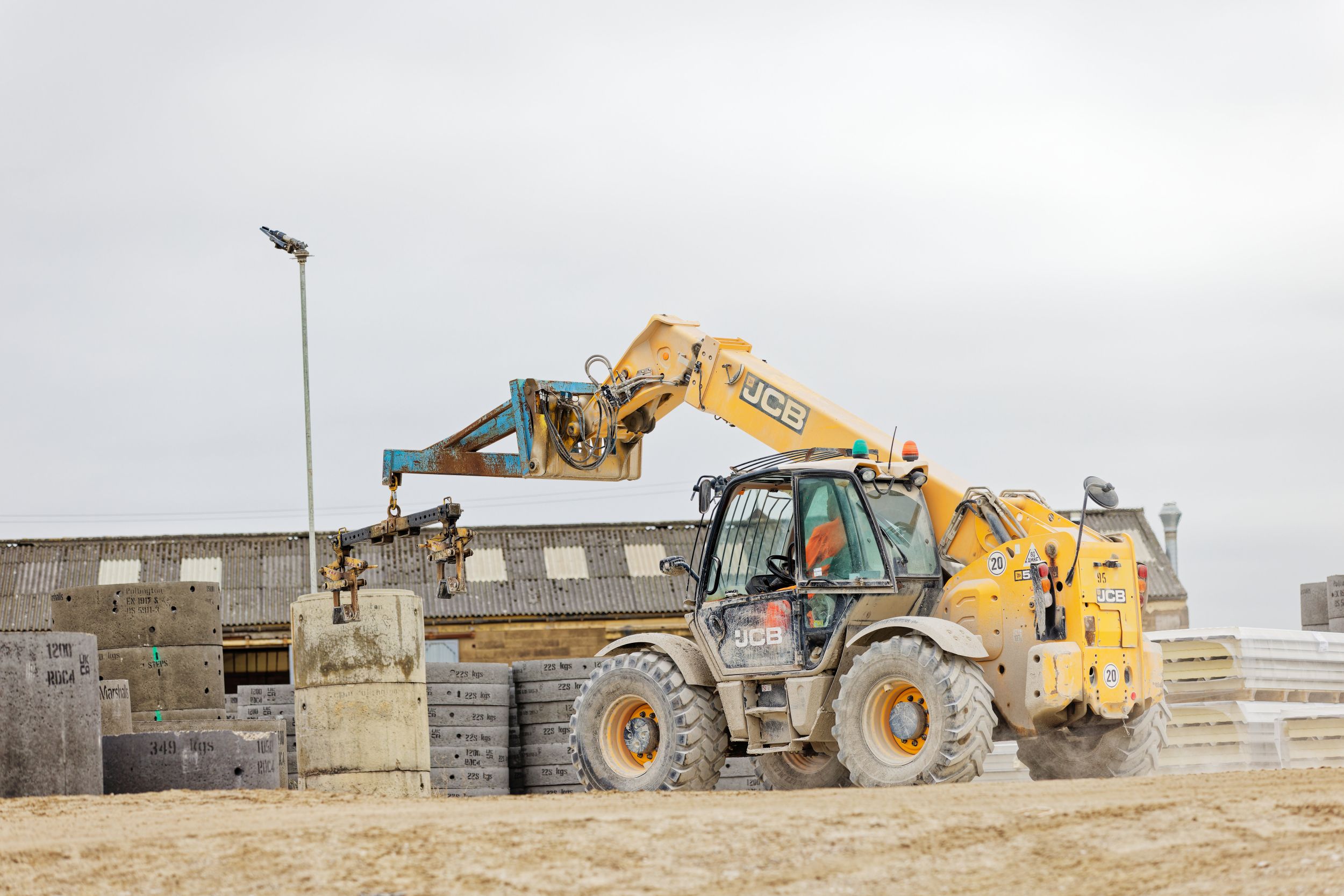 Telehandler moving concrete drainage rings around a manufacturing yard