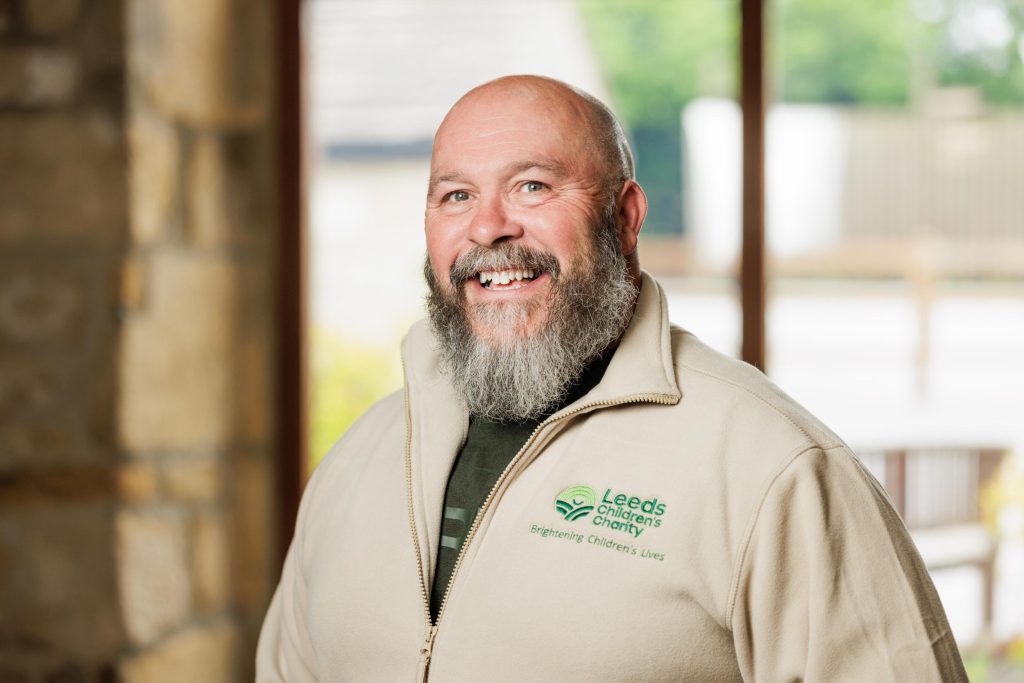 Bearded man in a branded fleece smiling for a workplace portrait